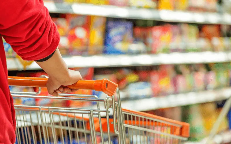 Shopper pushing trolley through supermarket aisle in Spain