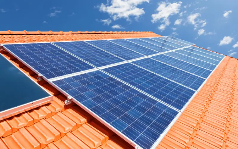 Solar panels on roof with clouds in the distance and blue sky