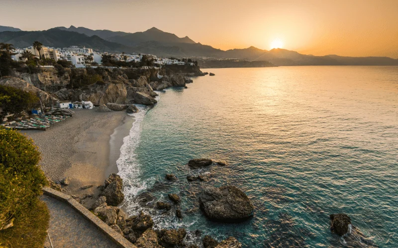 Sunset view over Nerja beach with turquoise sea and coastal village in Spain