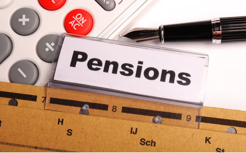 Office desk with pensions label, calculator, pen, and ruler for financial planning