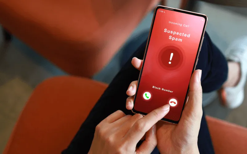 Person blocking a spam call on smartphone screen to avoid phone scams
