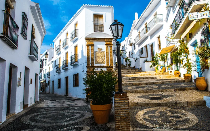 Traditional whitewashed village street in southern Spain with mosaic steps and flowers