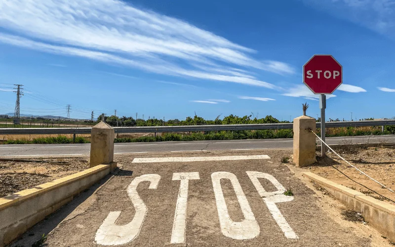 Stop sign at rural road intersection under blue sky in Spain