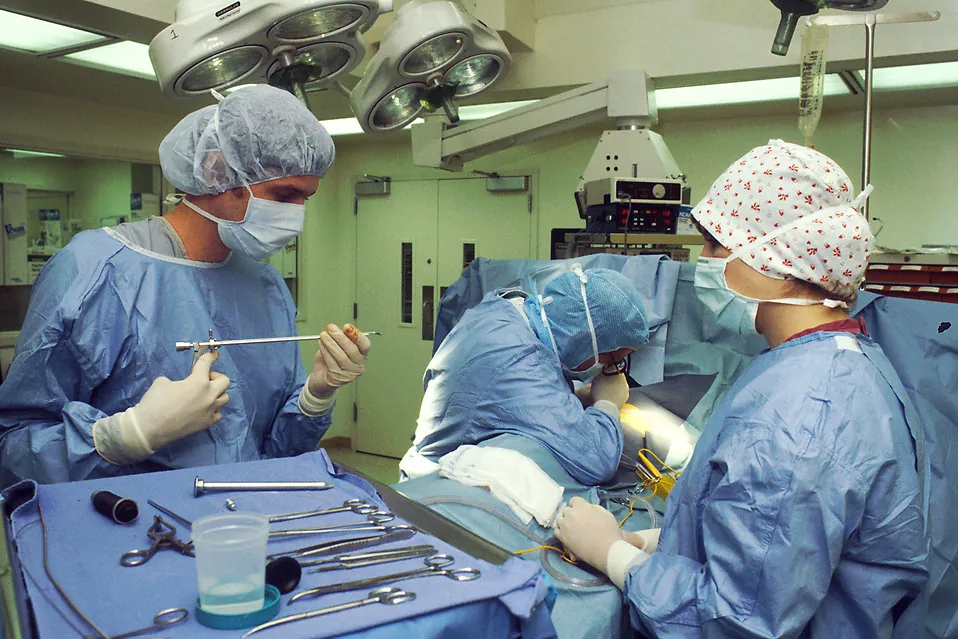 Medical team performing surgery in a hospital operating room with surgical tools prepared on sterile tray