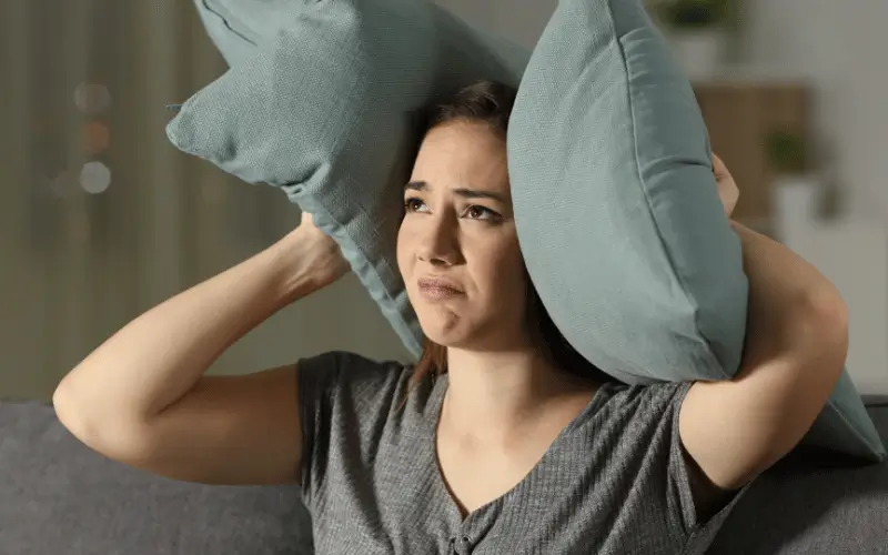 Woman blocking out the noise using two pillows
