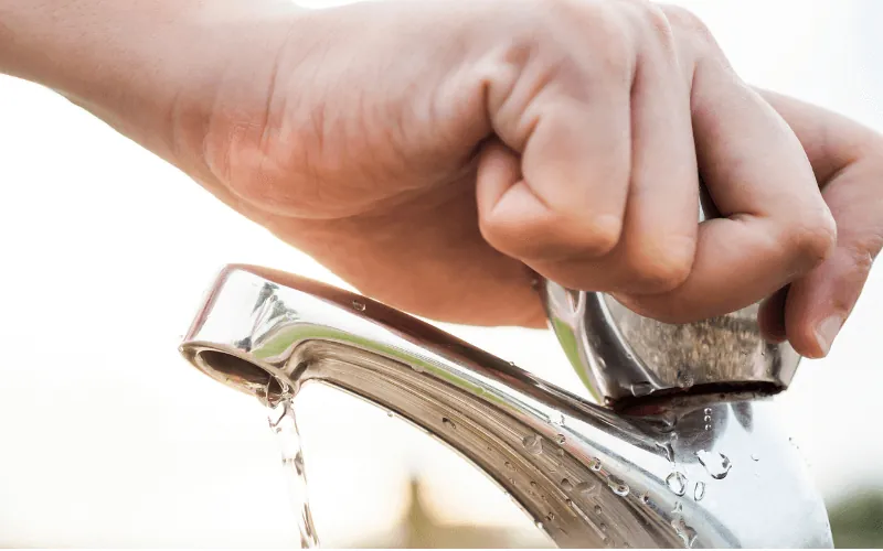 Hand turning off water tap to save water during drought in Spain