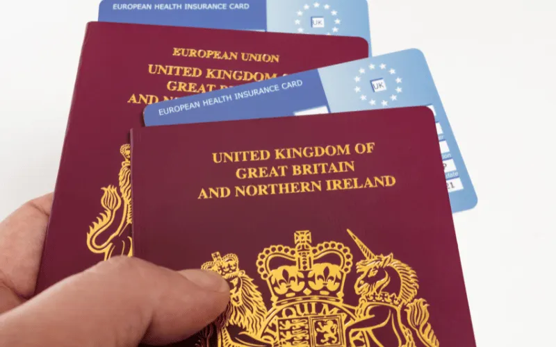UK passports and European Health Insurance Cards held in hand for travel preparation