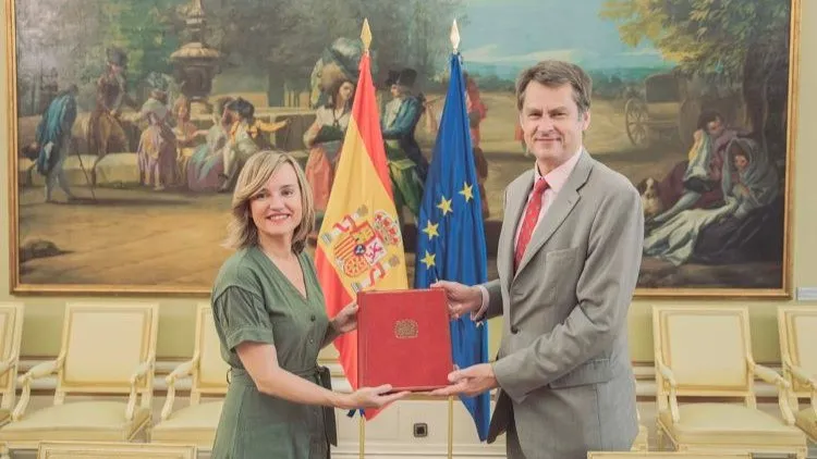UK and Spain officials holding agreement document in diplomatic ceremony