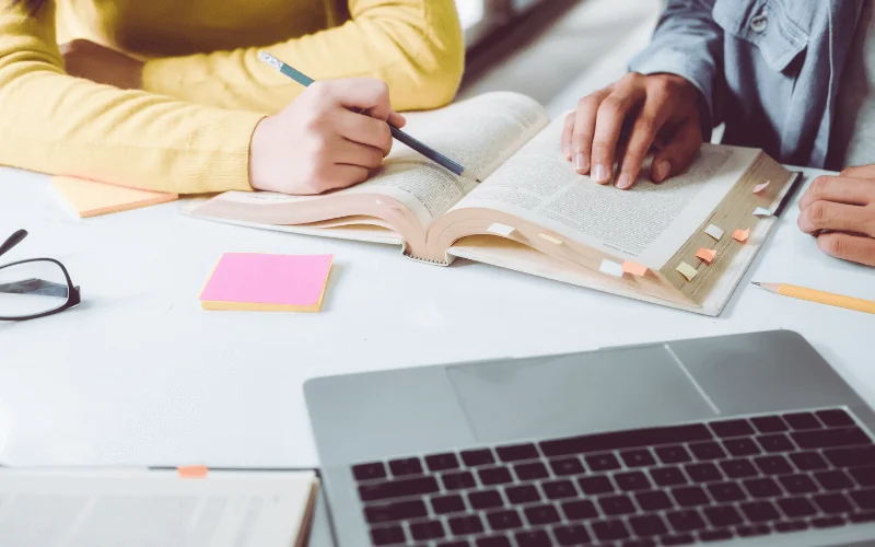 University students studying together with books and laptop on desk