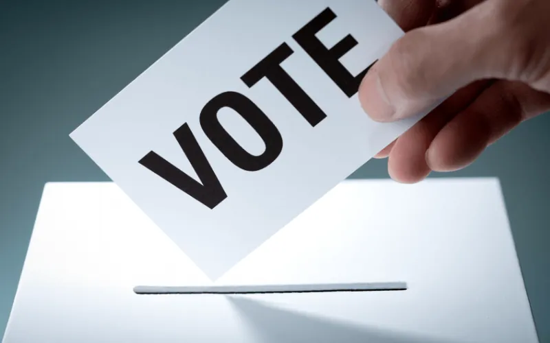Hand placing a vote card into a ballot box during municipal elections in Spain
