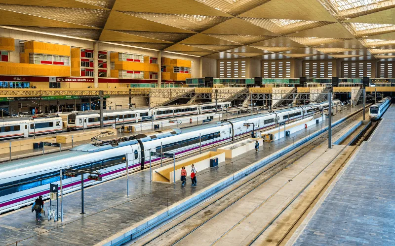 Interior view of Zaragoza train station with high-speed trains on multiple platforms